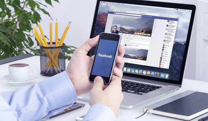homem segurando celular com logo do facebook na tela
